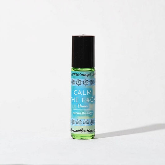 A small roll-on bottle of aromatherapy oil roller with a black cap and a light blue label reading 'CALM THE F*CK DOWN' and 'aromatherapy', photographed on a plain white background.