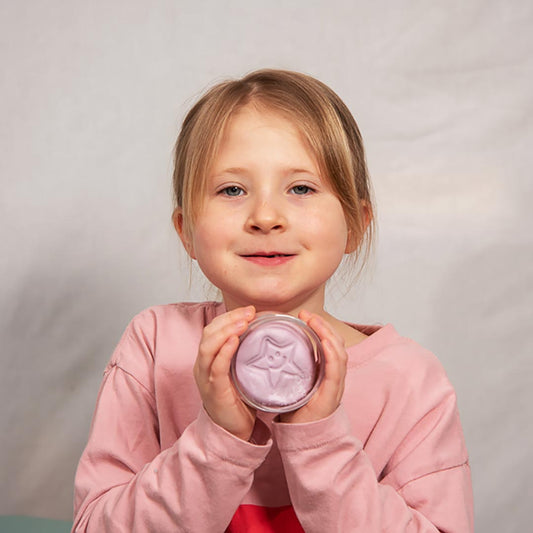 Young girl holding a Relax Aroma Putty container with a white lid against a plain background