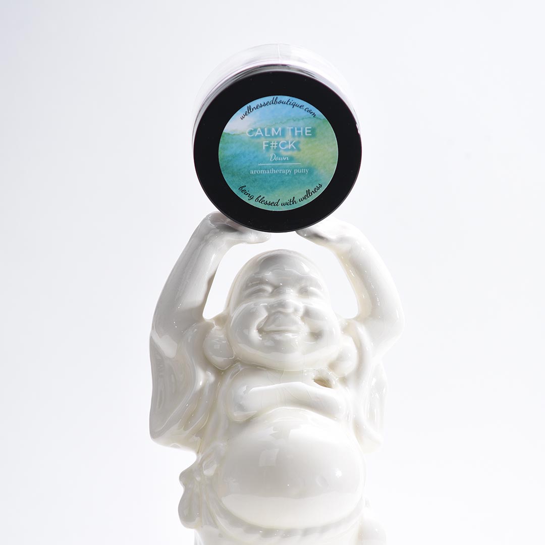White Buddha statue holding a container of Calm Down Aromatherapy Putty