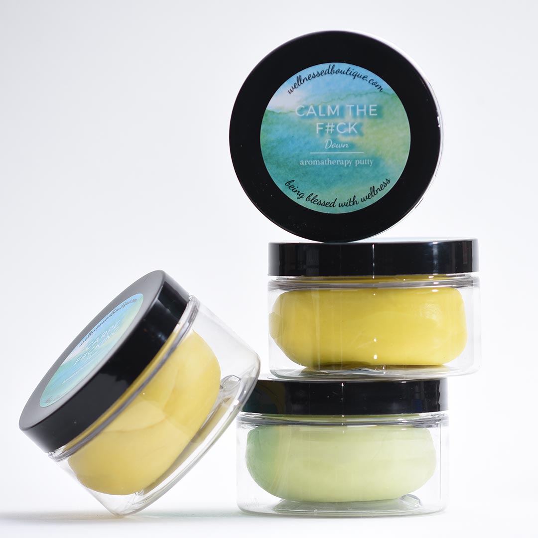 Four containers of Calm Down Aromatherapy Putty with black lids and labels on a white background
