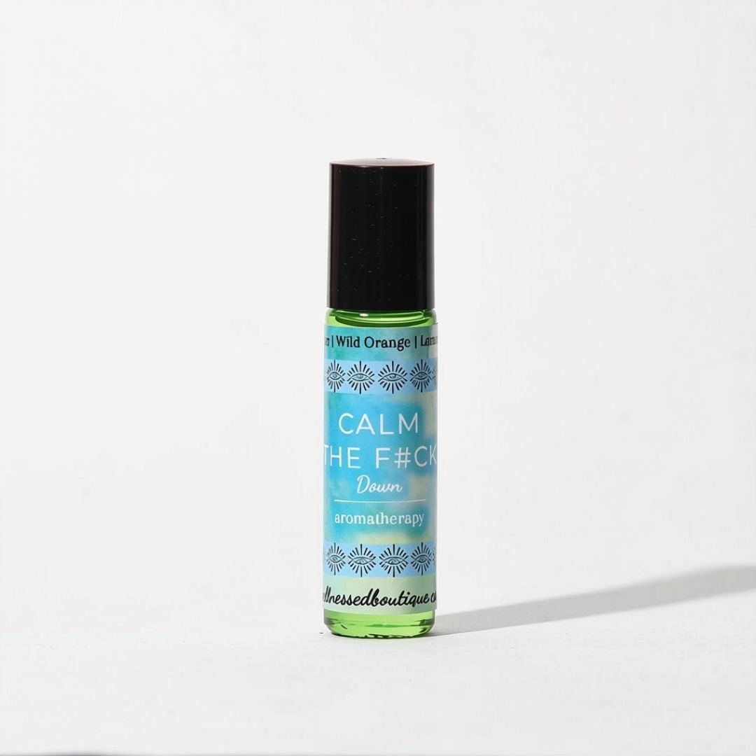 A small roll-on bottle of aromatherapy oil  roller with a black cap and a light blue label reading 'CALM THE F*CK DOWN' and 'aromatherapy', photographed on a plain white background.