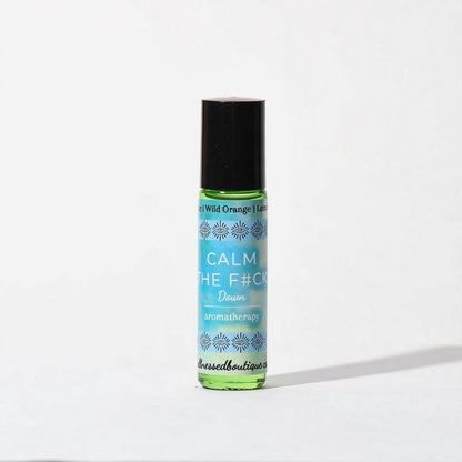 A small roll-on bottle of aromatherapy oil  roller with a black cap and a light blue label reading 'CALM THE F*CK DOWN' and 'aromatherapy', photographed on a plain white background.