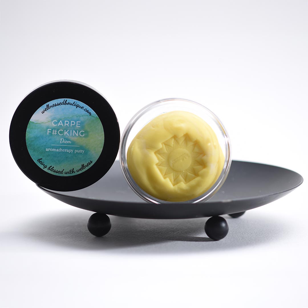 Yellow Carpe Diem aromatherapy sensory putty in a clear container with a black lid on a white background