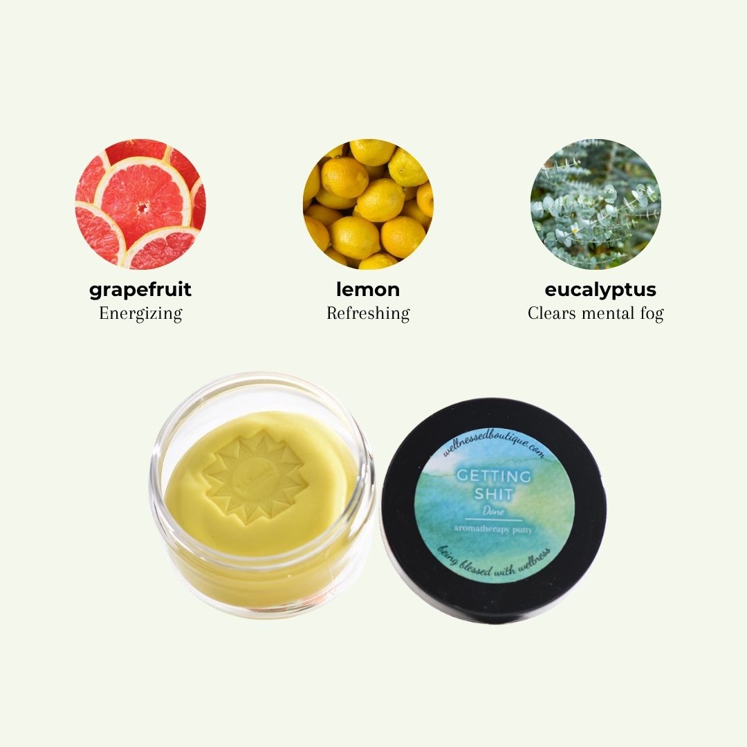 A small clear jar of Getting Shit Done Aromatherapy Putty beside a black round lid with a blue-green label reading 'GETTING SHIT DONE'. Above are three ingredient-style circles labeled grapefruit, lemon, and eucalyptus with text 'Energizing,' 'Refreshing,' and 'Clears mental fog.