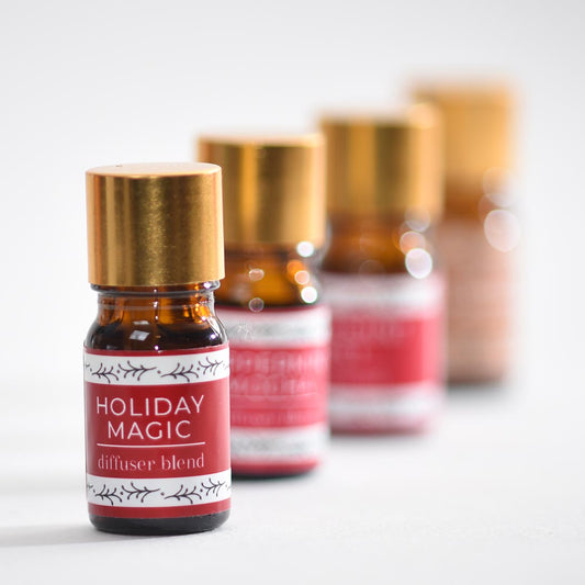 Bottle of 'Holiday Magic' diffuser blend with gold cap and red label on a white background