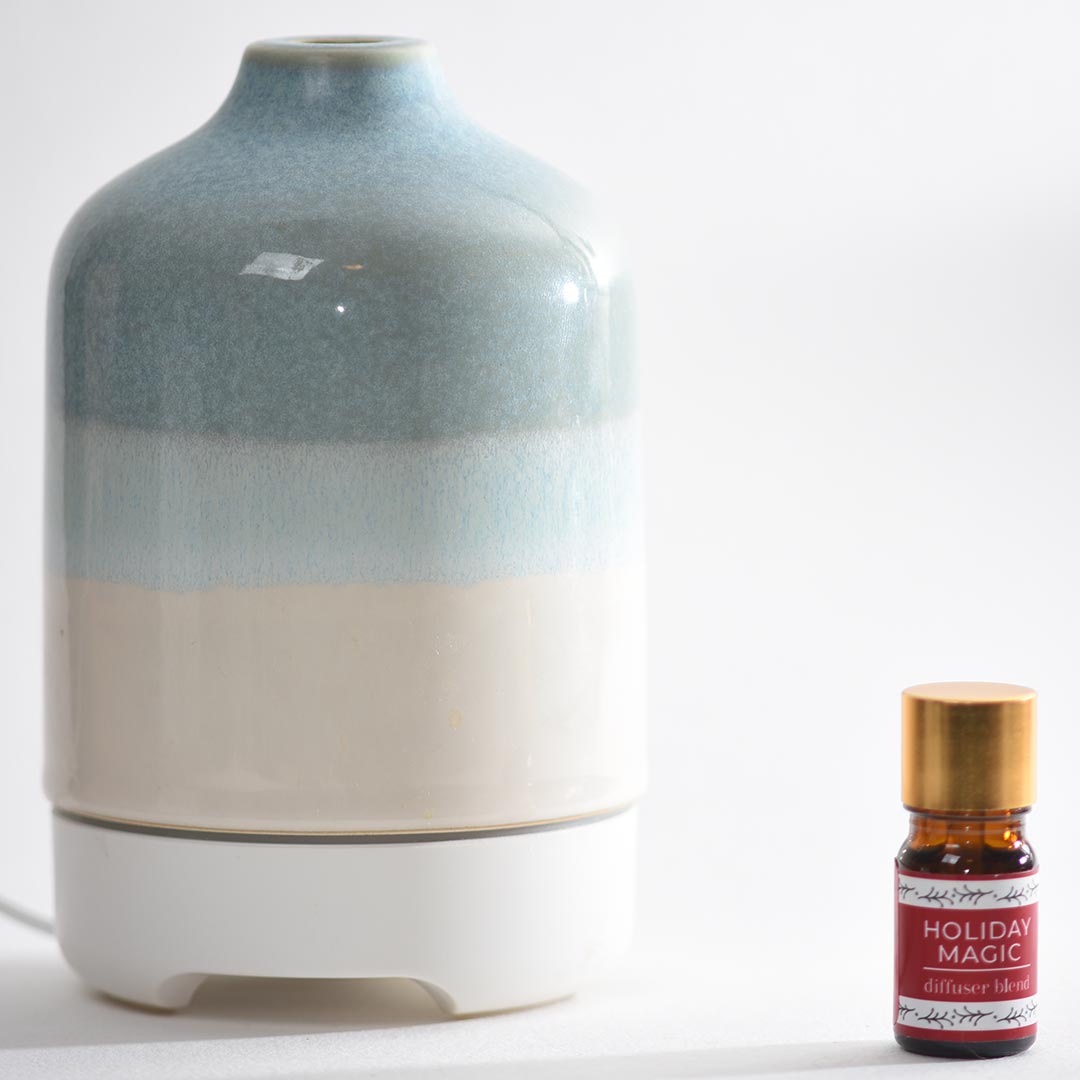 Decorative diffuser with a bottle labeled 'Holiday Magic diffuser blend' on a white background