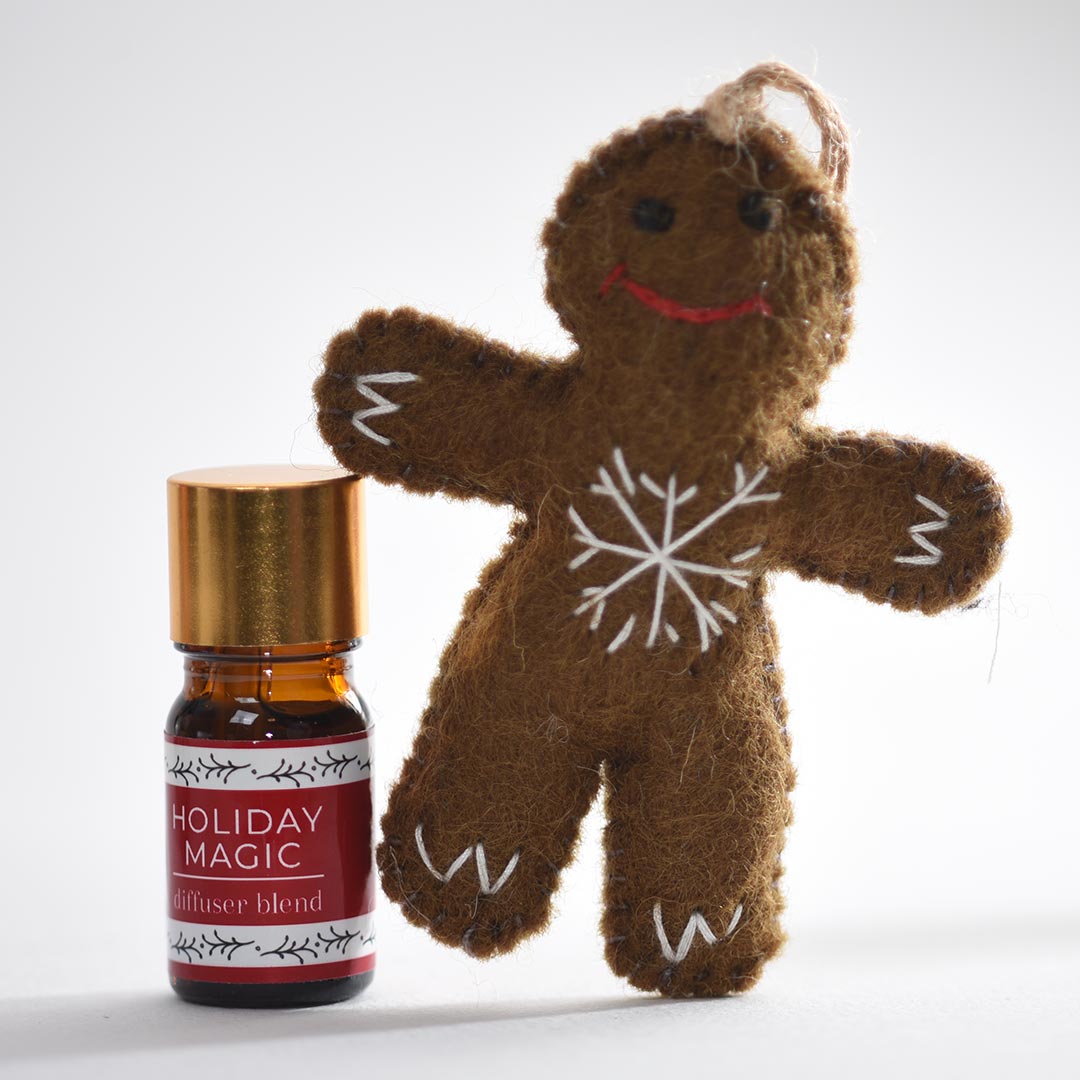 Gingerbread man ornament and 'Holiday Magic' diffuser blend bottle on a white background