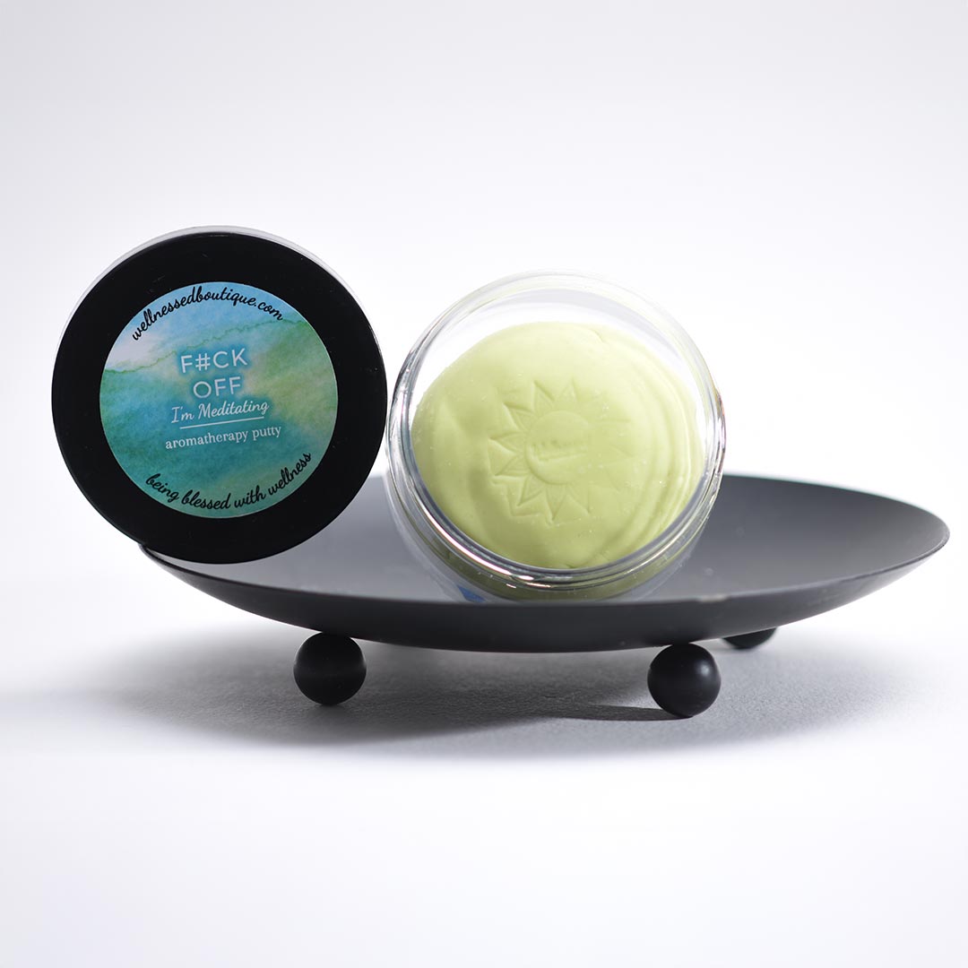I'm Meditating Aromatherapy putty in a clear container with a black lid on a gray stand.
