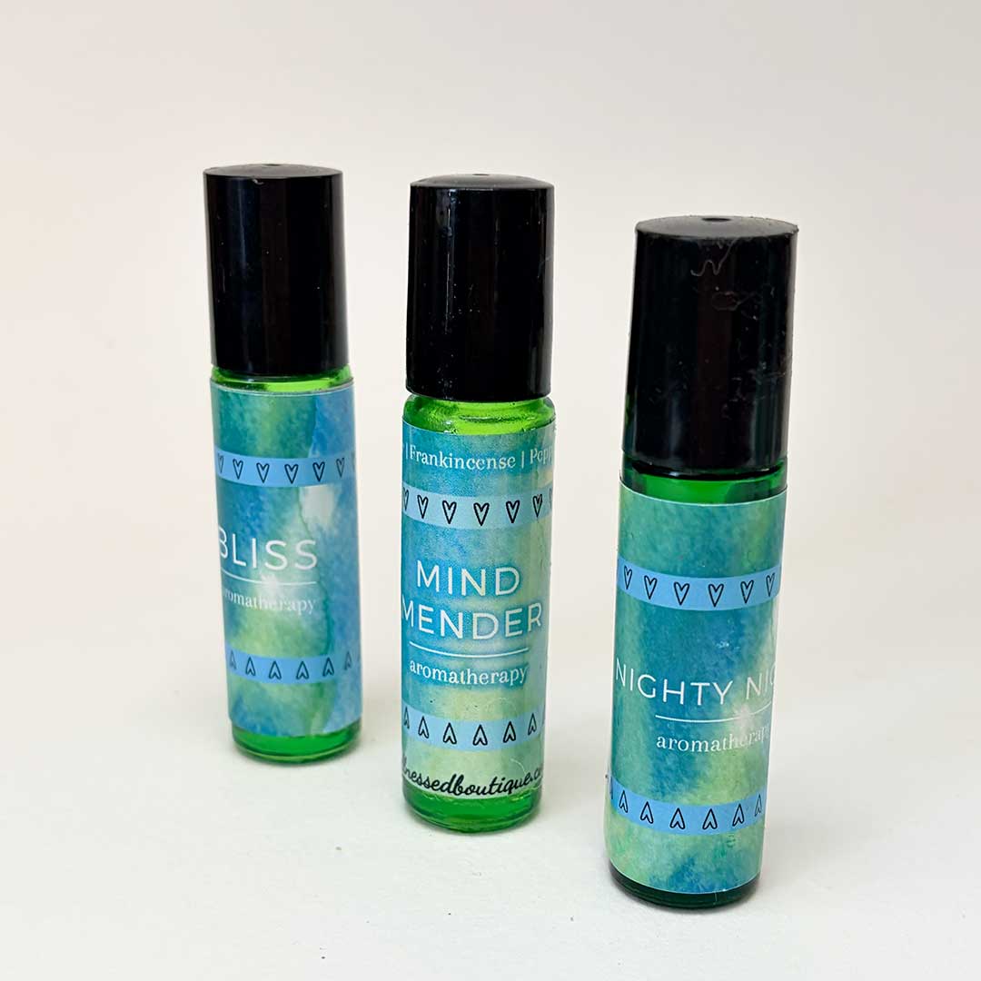 Three roller bottles with green and blue labels on a white background featuring Mind Mender Headache Relief Roll On in the center