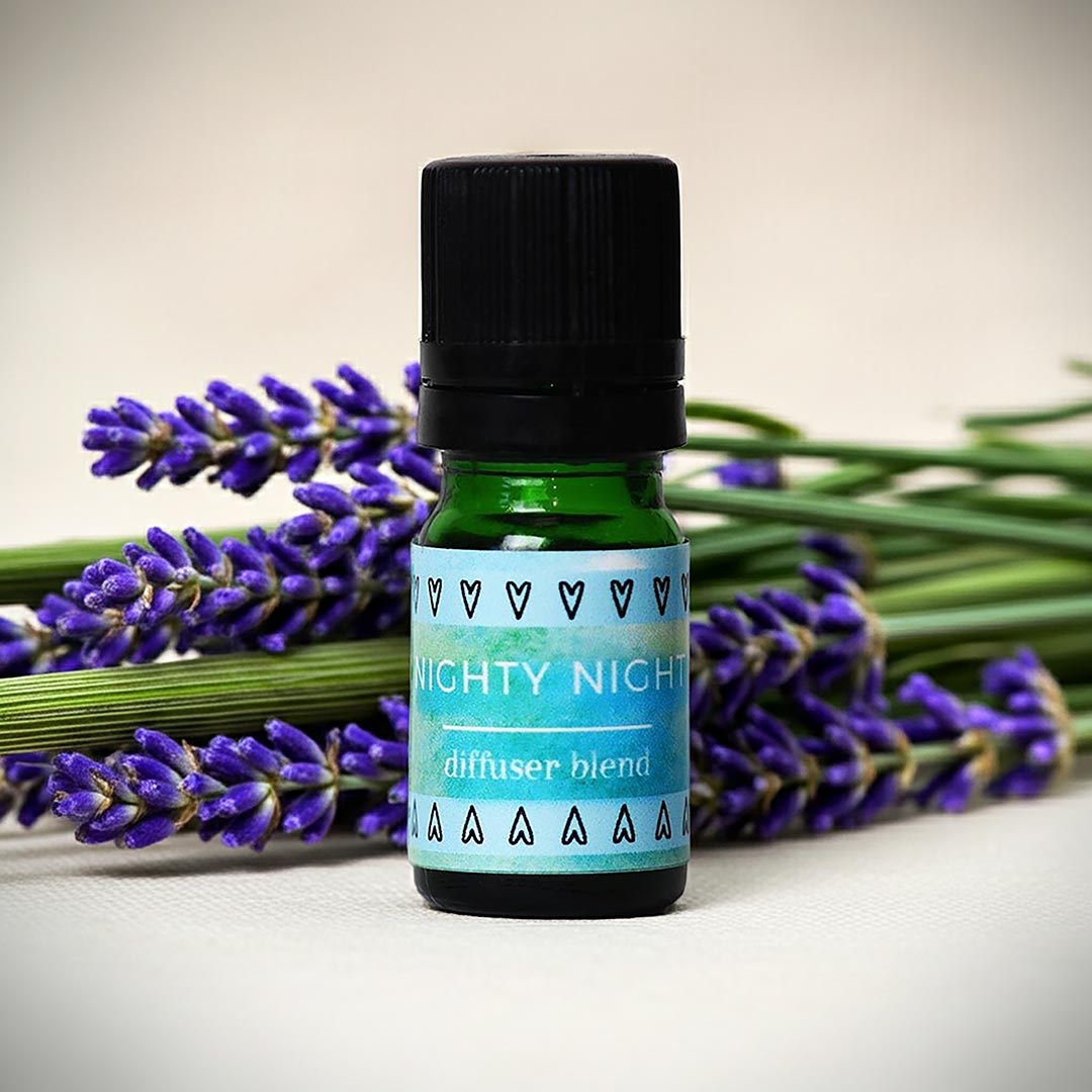 Bottle of Nighty Night sleep essential oilblend with lavender flowers on a light background
