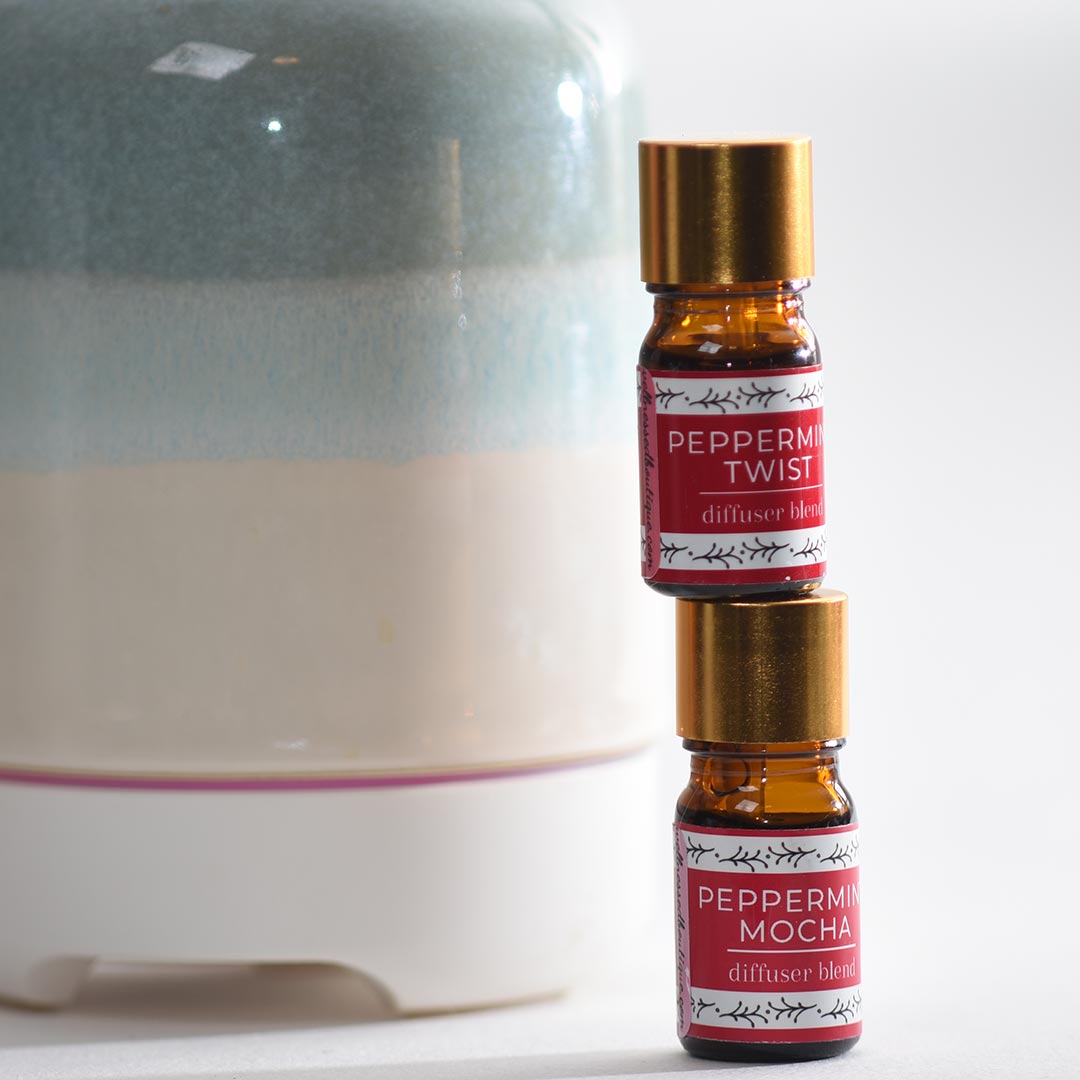 Two bottles of peppermint mocha diffuser blend in front of a diffuser.