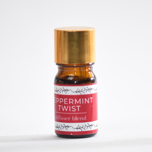 Bottle of peppermint twist diffuser blend with a gold cap on a white background