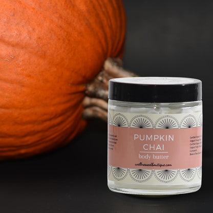 Jar of pumpkin chai body butter with a pumpkin in the background