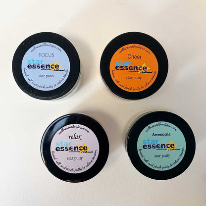 Four containers of star essence star aromatherapy putty with different colored labels on a white background.