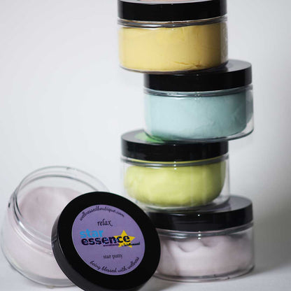 Stack of small Star Essence Aromatherapy Non Toxic Putty jars with colorful contents and a visible brand label on a white background