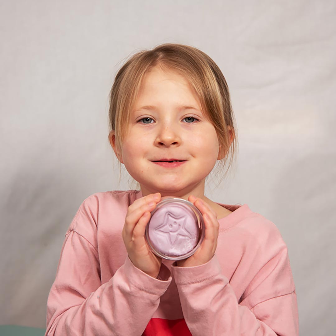 Young girl holding a Relax Aroma Putty container with a white lid against a plain background