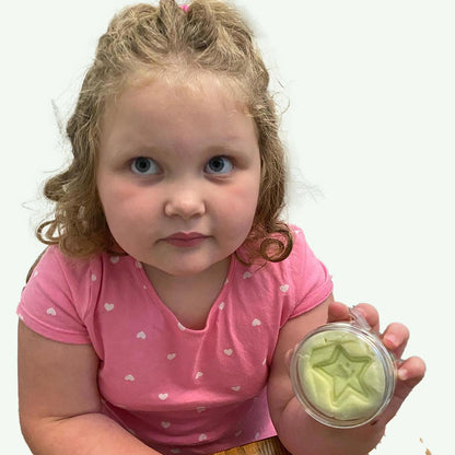 Child holding a container of Star Essence Awesome toy putty with a star-shaped object against a plain background